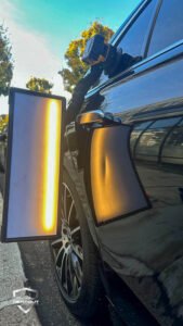 Dent Removal West London – Before the dent was removed from a black car door in West London, PDR light reflecting the dent.